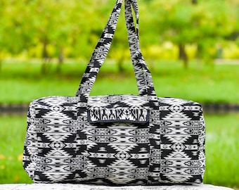 Puede incluir: Bolsa de viaje de lona negra y blanca con estampado geométrico y un bolsillo con cremallera en la parte delantera.
