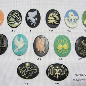 Könnte beinhalten: Eine Sammlung ovaler Cameo-Anhänger mit verschiedenen Designs. Die Cameos zeigen Bilder von Katze, Pferd, Pegasus, Einhorn, Katzen, Eule, Taube, Schmetterling, Schwänen, Pfau, Oktopus und Fledermaus. Der Text "WORLD OF HANDMADE" ist ebenfalls vorhanden.