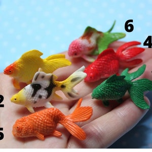 Puede incluir: Conjunto de diez juguetes de plástico de peces dorados de colores. Los peces son de varios colores, incluyendo rojo, amarillo, verde, naranja y blanco y negro. Los peces están numerados del 1 al 10.