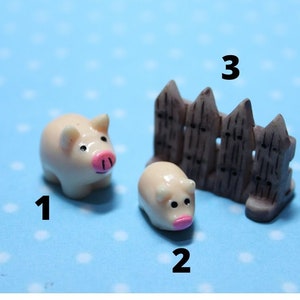 May include: Three miniature figurines: two pig figures with pink noses and a brown picket fence. The pig figures are cream colored and the fence is brown.
