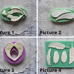 May include: Four silicone molds for baking. The first mold is purple and features a pair of angel wings with a heart in the center. The second mold is green and features a pair of angel wings. The third mold is purple and features a pair of angel wings with a heart-shaped opening in the center. The fourth mold is green and features five different feather shapes.