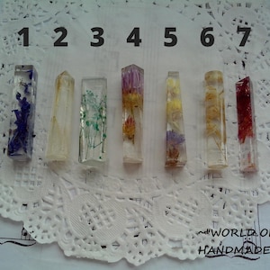 May include: Seven clear resin pendants with different dried flower arrangements. The pendants are numbered 1 through 7.