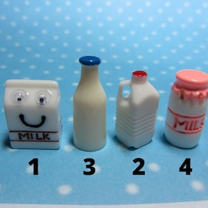 May include: Four miniature milk containers, including a carton with a smiling face, a glass bottle, a plastic jug, and a jar. The containers are white with blue, red, and pink accents. The carton has the word "MILK" printed on it.