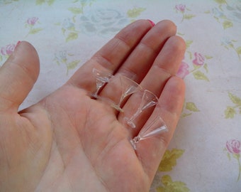Può includere: Quattro mini bicchieri da martini in vetro trasparente in una mano. I bicchieri sono abbastanza piccoli da stare sulla punta di un dito.
