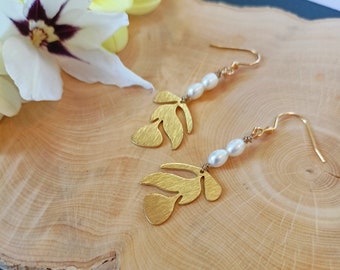 May include: Gold leaf earrings with pearl accents. The earrings feature a delicate leaf design with a textured finish. The pearls are white and are strung on a gold wire.