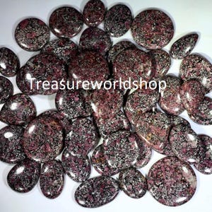 Peut inclure: Une collection de pierres lisses et polies avec un motif moucheté de noir et de rose. Les pierres sont de différentes tailles et formes, et certaines ont une forme légèrement ovale.