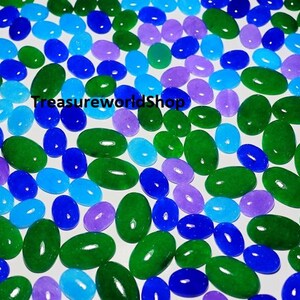 Könnte beinhalten: Eine Ansammlung ovalförmiger Edelsteine in verschiedenen Farben, darunter Grün, Blau, Hellblau und Lila. Die Edelsteine sind auf einer weißen Oberfläche verstreut und bilden ein farbenfrohes Muster. Der Text "TreasureworldShop" ist sichtbar.