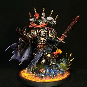 May include: A painted miniature figure of a warrior in black and gold armour with a red cape, holding a serrated sword. The figure features a skull-adorned crown, a pale face, and stands on a base decorated with skulls and fiery orange lava effects.