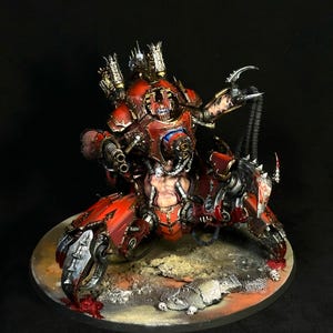 Puede incluir: Una figura de criatura mecánica roja y metálica con un torso central que presenta un pecho humanoide, múltiples extremidades articuladas con garras afiladas y armamento montado. La figura está sobre una base circular con escombros.