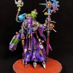 Op de afbeelding: Een geschilderd miniatuurfiguur met een paarse mantel met witte symbolen, mechanische ledematen en een hoge staf bekroond met een tandwielvormig blad. Het figuur bevat lichtgevende groene bussen en metalen zilveren onderdelen.
