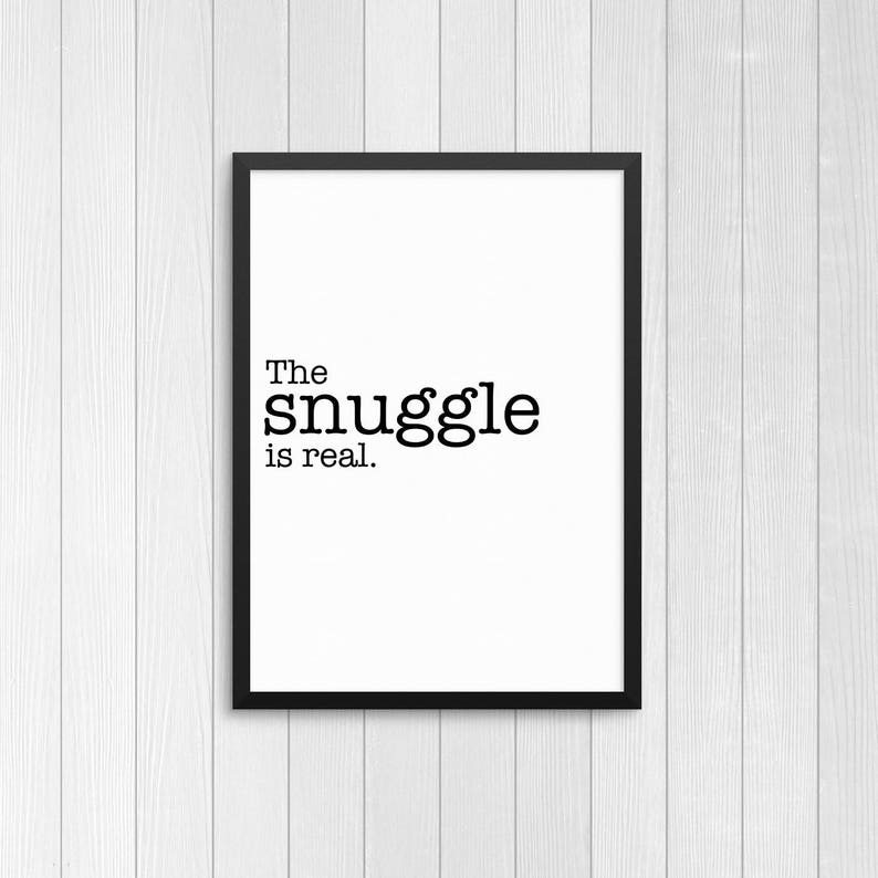 May include: Black and white typography print with the text "The snuggle is real." in a black frame.