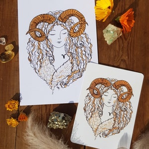 Puede incluir: Dos impresiones de arte imprimibles que presentan una ilustraci&oacute;n estilizada de una mujer con cabello rizado y cuernos de carnero. La mujer lleva un abrigo de piel blanco y tiene un s&iacute;mbolo del zod&iacute;aco en el pecho. Las impresiones est&aacute;n en papel blanco con un fondo blanco.