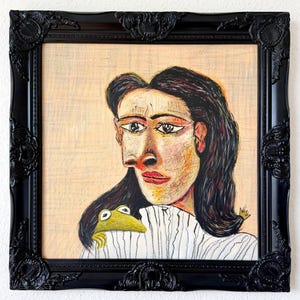 Könnte beinhalten: Eine gerahmte Zeichnung einer Person mit dunklem Haar und einem weißen Hemd mit Kragen, auf deren Schulter ein kleiner grüner Frosch sitzt. Das Kunstwerk befindet sich in einem dekorativen schwarzen, verzierten Rahmen mit detaillierten Schnitzereien.