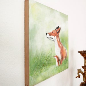 May include: A painting of a red fox with its eyes closed, standing in a field of green grass. The fox is looking up at the sky, and there is a small, brown fox cub nestled against its side.