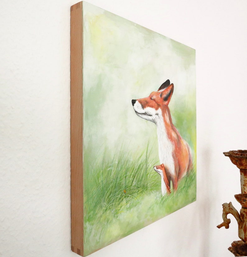 May include: A painting of a red fox with its eyes closed, standing in a field of green grass. The fox is looking up at the sky, and there is a small, brown fox cub nestled against its side.