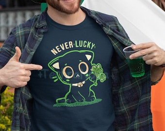 May include: A navy blue t-shirt with the words "NEVER LUCKY" above a green cartoon cat holding a shamrock. The image also includes a green and white hat and an Irish flag. The cat has large eyes and a bell collar.