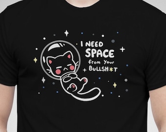 Könnte beinhalten: Schwarzes Unisex-T-Shirt mit einer Cartoon-Katze in einem Weltraumhelm, umgeben von Sternen. Das Shirt trägt den Text "I NEED SPACE from Your BULLSH*T". Unisex-Shirt-Stil.
