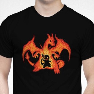 May include: Black t-shirt with a graphic of a fiery orange Pokemon character, Charizard, with a smaller Pokemon character, Charmander, inside. The text "etsy.com/shop/TechraNova" is visible at the bottom of the image.