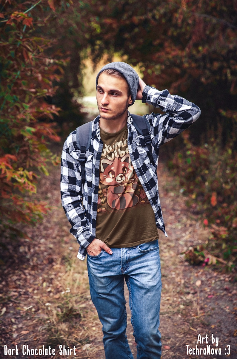 May include: A man wearing a dark chocolate brown t-shirt with a red panda graphic and the text "Autumn Vibes". He is also wearing a black and white plaid shirt, blue jeans, and a gray beanie.