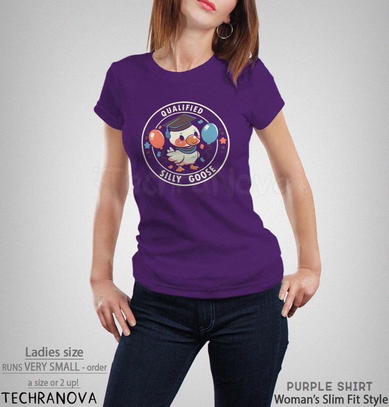 Może przedstawiać: Fioletowy T-shirt z grafiką przedstawiającą kresk&oacute;wkową gęś w czapce absolwenta trzymającą balony. Tekst "QUALIFIED SILLY GOOSE" jest nadrukowany w k&oacute;łku wok&oacute;ł gęsi.