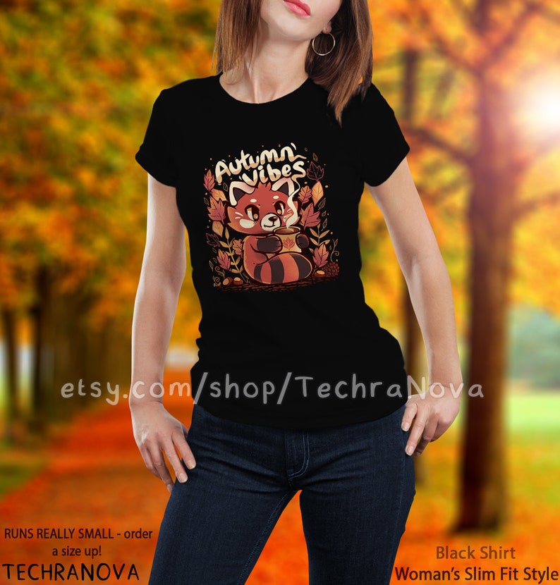 May include: Black t-shirt with a red panda illustration holding a cup of coffee and surrounded by autumn leaves. The text "Autumn Vibes" is above the panda.