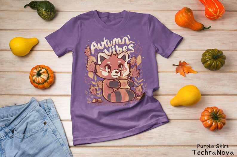 May include: Purple t-shirt with a red panda holding a cup of coffee and surrounded by autumn leaves. The text "Autumn Vibes" is printed on the shirt.