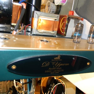 May include: A Shindo Laboratory D'Yquem audio amplifier featuring a dark green chassis with a black oval nameplate. The front panel displays the text D'Yquem, Parallel Single, and SHINDO LABORATORY TOKYO JAPAN. Two vacuum tubes are visible on top.