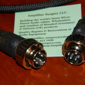 May include: Close-up of two black audio cables with gold-plated connectors. The cables are labeled "Amplifier Surgery".