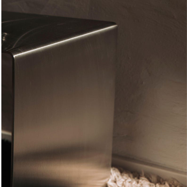 May include: Close-up of a brushed stainless steel surface. The surface is smooth and reflective, with a slight sheen.
