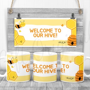 May include: Three white ceramic mugs with a bee and honeycomb design. The mugs have the text "Welcome to our hive!" printed on them.