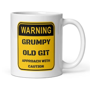 Puede incluir: Taza de cerámica blanca con un diseño de señal de advertencia en negro y amarillo. La señal dice "WARNING GRUMPY OLD GIT APPROACH WITH CAUTION" en texto negro. La taza tiene un asa curva.