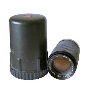 Puede incluir: Un objetivo de cámara negro con una tapa de objetivo negra. El objetivo tiene el texto "1/1.8 58" y "PENTEK" impreso en él.