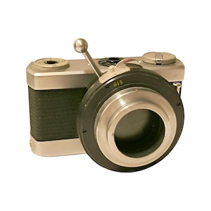 May include: A silver and black vintage camera with a lens cap and a lever on the top. The camera has a black leather covering and a silver metal body.