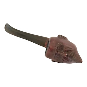 Puede incluir: Una pipa de cerámica marrón y negra con una cara humana tallada en la cazoleta.