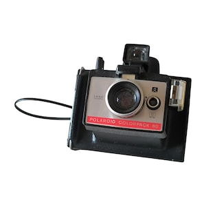 May include: A black Polaroid Colorpack 80 instant camera with a silver lens and a black strap. The camera has a red label that says "POLAROID COLORPACK 80" and a silver label that says "LAND CAMERA".