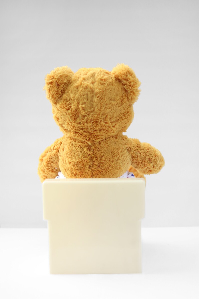 Puede incluir: Un oso de peluche marr&oacute;n sentado en un orinal blanco.