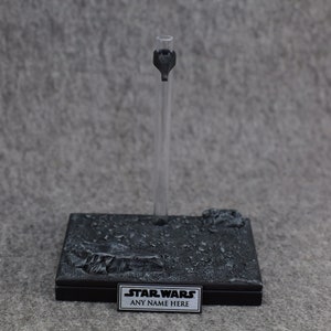 May include: Black display stand with a textured base and a clear plastic rod. The base has a silver plaque with the text "STAR WARS ANY NAME HERE".