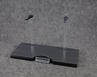 May include: A gray plastic display stand with two clear acrylic rods and black plastic arms. The stand has a silver plaque with the text "STAR WARS" and "ANY NAME HERE".