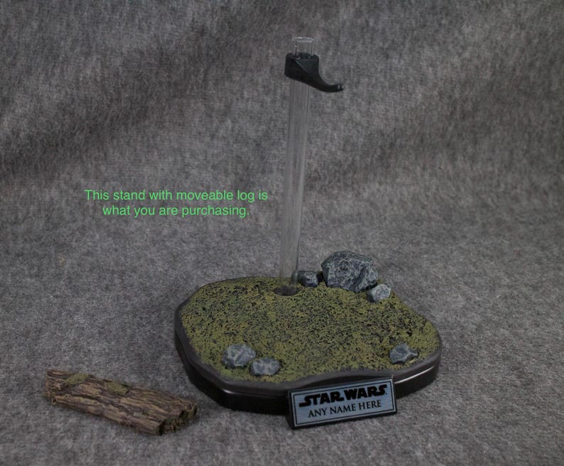 May include: A black plastic display stand with a removable log, rocks, and green foliage. The stand has a black plaque with the text "STAR WARS ANY NAME HERE".