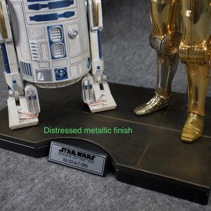 May include: A distressed metallic finish base with a silver plaque that reads "STAR WARS RETURN OF THE JEDI R2-D2 & C-3PO".  The base features a silver and gold robot figurine.