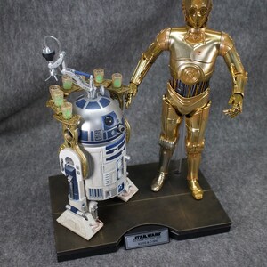 May include: A gold-colored C-3PO Star Wars action figure stands next to a blue and white R2-D2 action figure. Both figures are on a black base with a gold trim. The base has a plaque that reads "STAR WARS Episode IV: A New Hope R2-D2 & C-3PO".