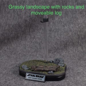 May include: A miniature grassy landscape with rocks and a movable log. The base is black with a clear acrylic stand. The base has a black plaque with the text "STAR WARS ANY NAME HERE".