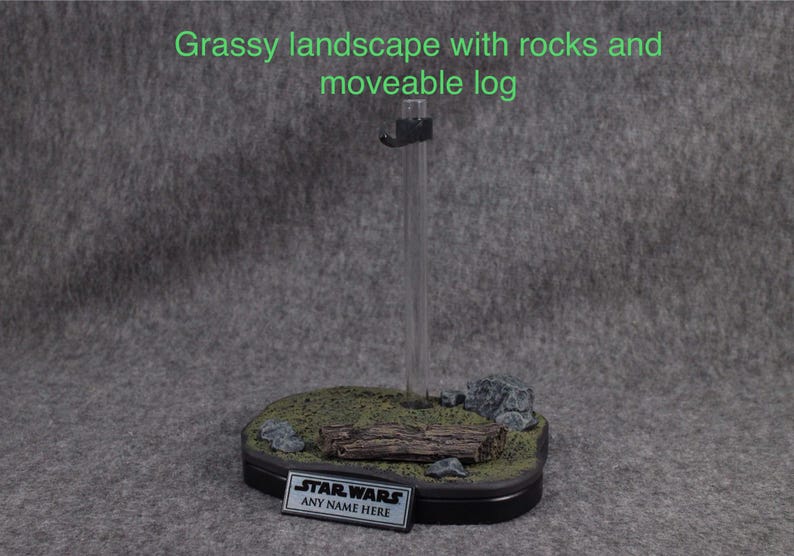 May include: A miniature grassy landscape with rocks and a movable log. The base is black with a clear acrylic stand. The base has a black plaque with the text "STAR WARS ANY NAME HERE".