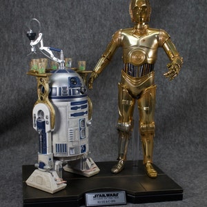 May include: A gold-colored C-3PO Star Wars action figure stands next to a white and blue R2-D2 action figure. Both figures are on a black base with a silver plaque that reads "Star Wars Return of the Jedi R2-D2 & C-3PO".