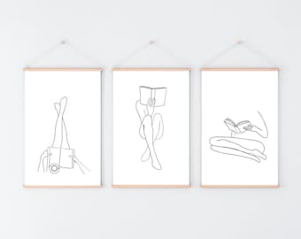 May include: Three black and white line drawings of people reading books. The drawings are framed and hung on a white wall.