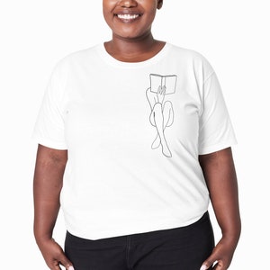 Op de afbeelding: Een wit T-shirt met een lijntekening van een persoon die met een boek op hun hoofd zit.