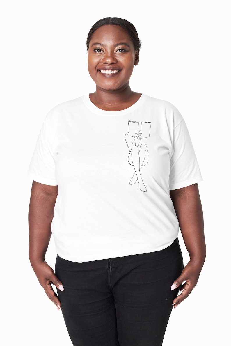 Op de afbeelding: Een wit T-shirt met een lijntekening van een persoon die met een boek op hun hoofd zit.