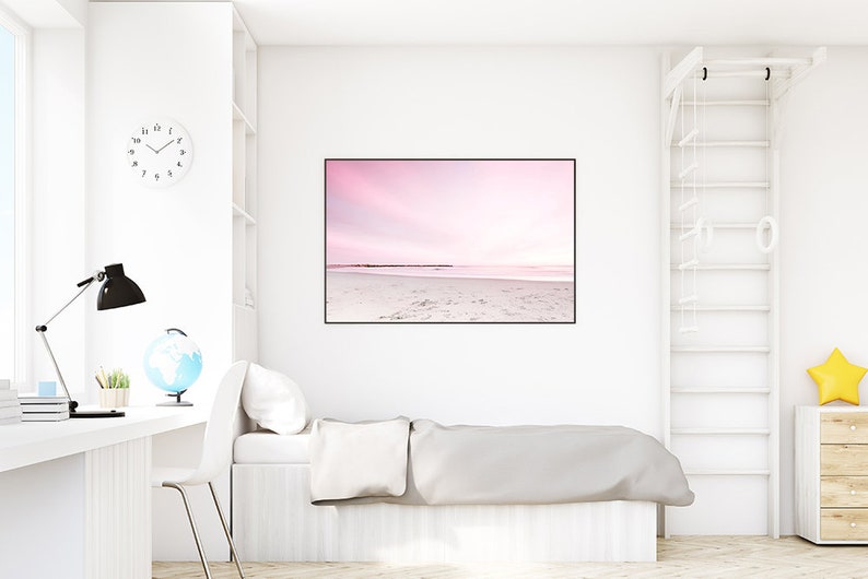 May include: A white bedroom with a bed, a desk, a globe, a lamp, a clock, and a framed photograph of a pink sunset over a beach.