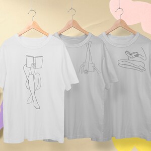Op de afbeelding: Drie witte T-shirts met zwarte lijntekeningen van figuren. De figuren zijn allemaal in verschillende poses, &eacute;&eacute;n leest een boek, &eacute;&eacute;n zit met haar benen omhoog en &eacute;&eacute;n zit met haar benen gekruist.