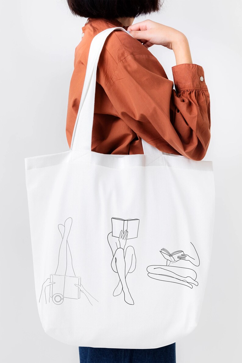 Op de afbeelding: Witte tote bag met een zwarte lijntekening van drie mensen die boeken lezen. De mensen zijn getekend in een minimalistische stijl.